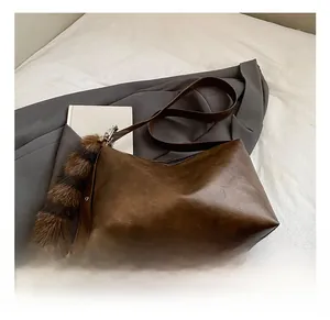 Detail of vintage brown PU leather tote bag with plush tail charm on a casual setting