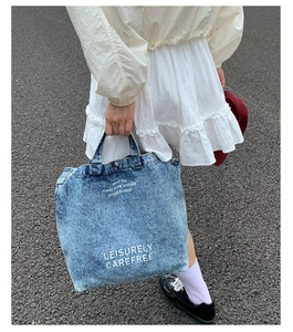 Vue de rue extérieure d'un sac cabas en jean bleu avec impression de texte blanc Leisurely