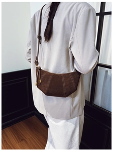 Detail view of dark brown suede croissant bag with stitched panels and decorative knots