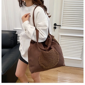 Detail of plush teddy patch on dark brown suede bucket shoulder bag for autumn winter