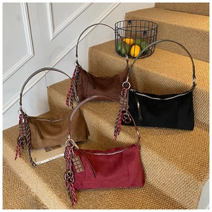 Vue détaillée de quatre sacs en daim rouge, noir et marron avec breloques décoratives