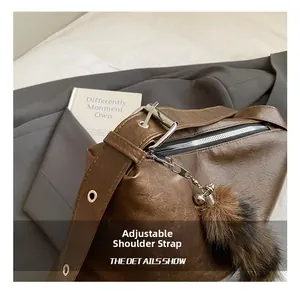 Detail view of the adjustable leather shoulder strap with silver buckle on the retro bag