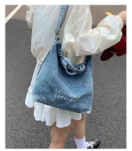 Vue de rue extérieure d'un grand sac cabas en jean vintage avec lettrage blanc