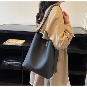 Détail du sac seau en cuir grainé noir avec fermoir rotatif en métal doré chic