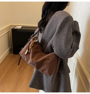 Détail du sac hobo en daim marron à motif léopard avec un pendentif perlé ethnique