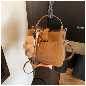 Detail of caramel brown leather bucket bag featuring Inerfil logo and decorative tassel