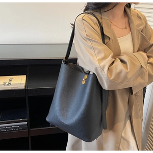 Détail du sac seau noir en cuir grainé avec fermoir doré et large bandoulière réglable