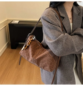 Gros plan du sac bandoulière léopard avec pendentif en perles et plaque métallique
