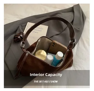Détail de la capacité interne d'un sac demi-lune en daim marron avec objets du quotidien