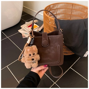 Detail of vintage brown bucket bag with MERFIL logo and cute plush bear keychain charm