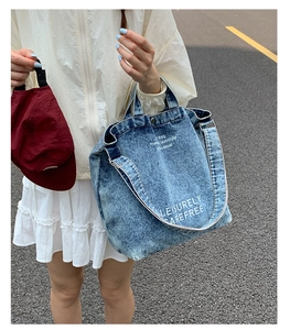 Détail du sac cabas en denim délavé bleu avec inscription graphique blanche