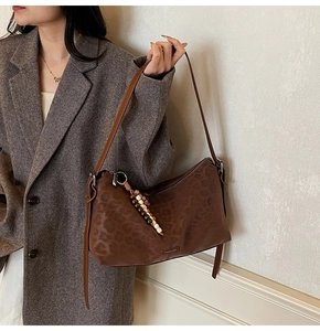 Détail du sac bandoulière léopard avec pompon perlé et boucles métalliques argentées