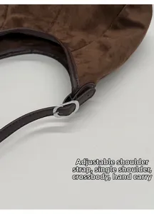 Détail de la bandoulière réglable avec boucle en métal argenté sur sac en daim marron