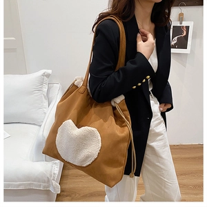 Detail shot of large brown suede tote bag with white fleece heart and drawstring design