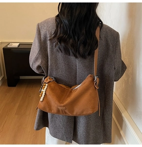 Gros plan d'un sac bandoulière en daim caramel avec fermeture éclair et perles