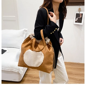 Brown suede tote bag with white faux shearling trim shown in a warm indoor setting