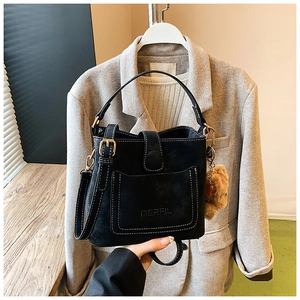 Detail of black matte bucket bag with gold hardware and a cute plush bear charm