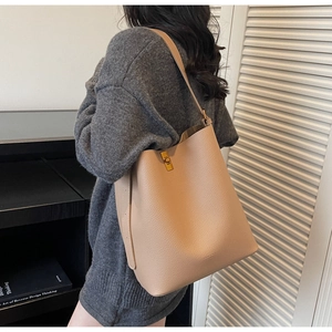 Gros plan d'un sac seau en cuir abricot avec grain texturé et fermoir en métal doré