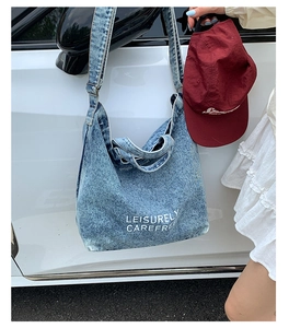 Détail du cabas en jean bleu délavé avec texte accroché à une poignée de voiture