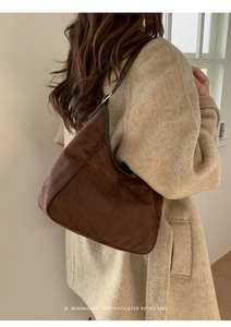 Détail d'un sac hobo en daim marron avec bandoulière réglable et boucle en métal argent