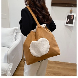 Detail of large brown suede tote bag with white plush heart and fuzzy trim accents