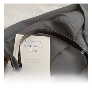 Détail du sac à bandoulière en daim marron foncé avec sangle en cuir et boucles en métal