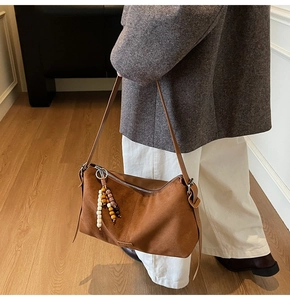 Gros plan d'un sac bandoulière en daim marron avec pendentif décoratif en perles ethniques
