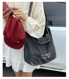 Photo lifestyle d'un sac cabas en denim gris délavé avec texte blanc brodé dessus