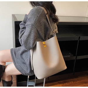 Détail du sac seau en cuir avoine avec fermoir tournant doré et texture grainée chic
