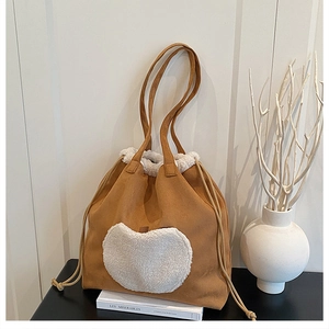 Detail of a brown suede tote bag with white fleece heart pocket and drawstring closure