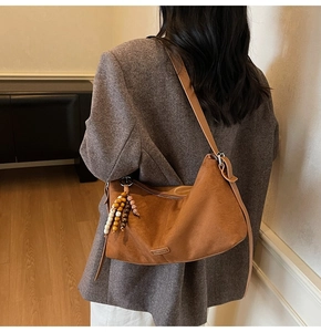 Vue détaillée du sac croissant marron mat avec breloque en perles rétro et logo en métal