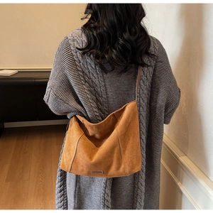 Detailed view of brown suede tote bag featuring contrast stitching and leather patch design