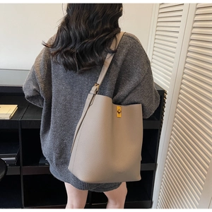Détail du sac seau en cuir gris avec un fermoir rotatif doré poli et bandoulière réglable
