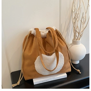Detail of caramel suede tote bag with white faux shearling trim and drawstring closure