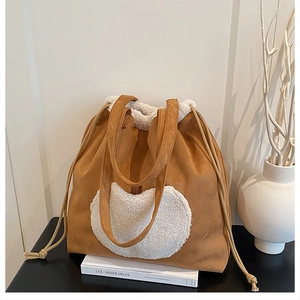 Detail of a brown faux suede tote bag featuring a white sherpa heart patch and drawstrings