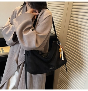 Détail du sac à bandoulière noir minimaliste avec perles bohèmes et étiquette métallique