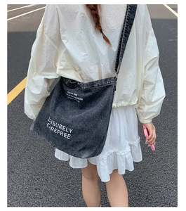 Vue arrière du modèle portant un grand sac fourre-tout en denim gris foncé à bandoulière large