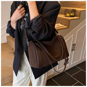 Side view of dark brown leather Boston bag with vintage metallic lock and shoulder strap