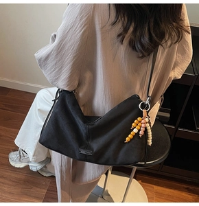 Détail du sac bandoulière noir en nylon souple avec breloque en perles colorées