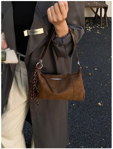 Détail du sac polochon en daim marron foncé avec bandoulière tissée et fermeture éclair