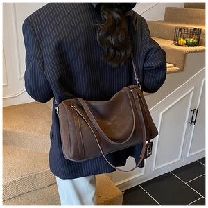 Brown textured retro shoulder bag with padlock detail shown in a lifestyle setting