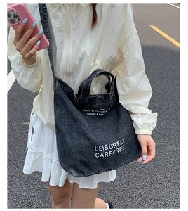 Détail du sac cabas en denim gris avec texte blanc et fermeture en métal robuste