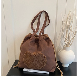 Detail of vintage brown suede tote with plush heart patch and drawstring closure