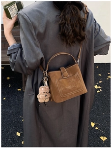 Detail of vintage brown suede bucket bag with stitching and plush bear charm