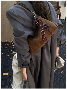 Détail du sac à bandoulière en daim marron foncé avec corde tressée et pendentif