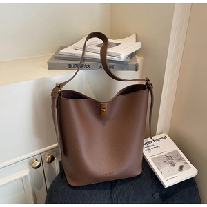Vue détaillée du sac seau en cuir marron avec fermoir tournant doré vintage et logo