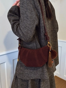 Brown suede dumpling crescent bag with tassels worn by model in grey wool suit