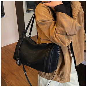 Detail of black Boston leather bag showing silver metal padlock and adjustable strap
