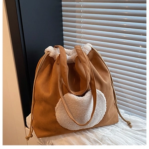 Detail of large brown suede bucket bag with white fleece heart and drawstring trim