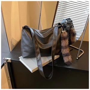 Detail of black slouchy tote bag with leather texture and faux fur tail accessory